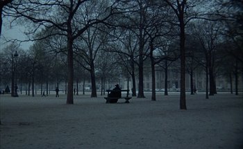 Movie still from “F for Fake” (1973), directed by François Reichenbach – A person sitting on a bench in a park; Extreme Wide shot, High angle