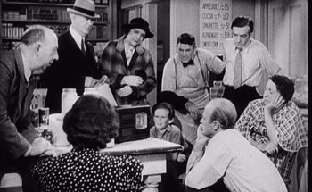 Movie still from “F for Fake” (1973), directed by François Reichenbach – A group of people sitting around a table; Medium shot, High angle