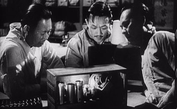 Movie still from “F for Fake” (1973), directed by François Reichenbach – A group of people sitting around a table with candles; Medium shot, Low angle