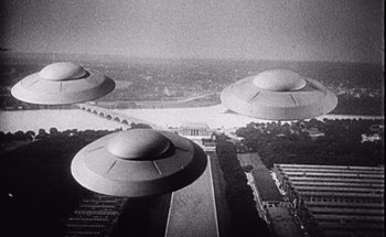 Movie still from “F for Fake” (1973), directed by François Reichenbach – A black and white photo of three flying saucers; Extreme Wide shot, High angle