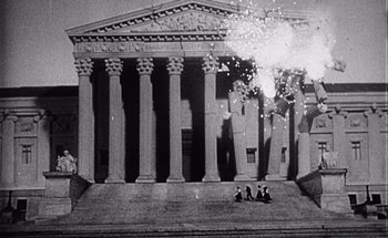 Movie still from “F for Fake” (1973), directed by François Reichenbach – A black and white photo of people sitting on steps in front of a building; Extreme Wide shot, Low angle