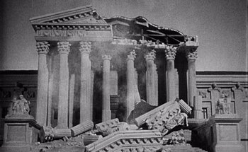 Movie still from “F for Fake” (1973), directed by François Reichenbach – A black and white photo of a ruined building; Extreme Wide shot, Low angle