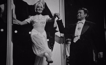 Movie still from “F for Fake” (1973), directed by François Reichenbach – A man and a woman in formal wear dancing; Medium shot, Low angle