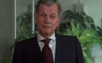 Movie still from “F for Fake” (1973), directed by François Reichenbach – An older man wearing a suit and tie; Close Up shot, Low angle