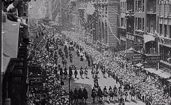 Movie still from “F for Fake” (1973), directed by François Reichenbach – A large crowd of people riding horses down a street; Extreme Wide shot, High angle