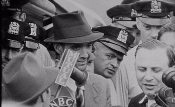 Movie still from “F for Fake” (1973), directed by François Reichenbach – Black and white photograph of men in hats and ties; Close Up shot, Over the shoulder angle
