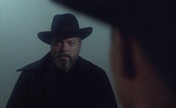Movie still from “F for Fake” (1973), directed by François Reichenbach – A man with a beard and a black hat is looking into a mirror; Close Up shot, Over the shoulder angle