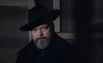 Movie still from “F for Fake” (1973), directed by François Reichenbach – A man with a gray beard wearing a black hat; Close Up shot, Low angle