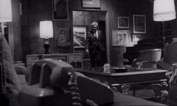 Movie still from “Faces” (1968), directed by John Cassavetes – A man in a suit is standing in a room; Wide shot, High angle