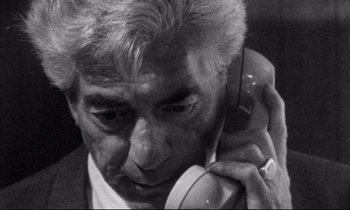 Movie still from “Faces” (1968), directed by John Cassavetes – An older man talking on a cell phone while wearing a suit; Close Up shot, High angle