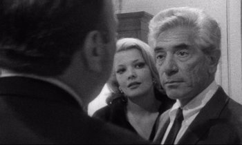 Movie still from “Faces” (1968), directed by John Cassavetes – A man and a woman standing next to each other in a room; Close Up shot, Over the shoulder angle