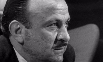 Movie still from “Faces” (1968), directed by John Cassavetes – An old black and white photo of a man with a mustache; Close Up shot, Low angle