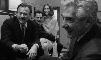 Movie still from “Faces” (1968), directed by John Cassavetes – A black and white photo of a group of men and a woman; Medium shot, Over the shoulder angle