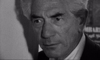 Movie still from “Faces” (1968), directed by John Cassavetes – A black and white photo of a man in a white shirt; Close Up shot, Over the shoulder angle