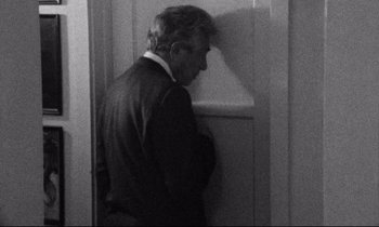 Movie still from “Faces” (1968), directed by John Cassavetes – An older man leaning against a wall in front of a door; Medium shot, Over the shoulder angle