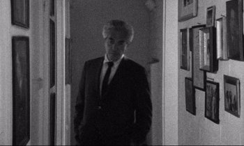 Movie still from “Faces” (1968), directed by John Cassavetes – A black and white photo of a man in a suit and tie; Medium shot, Over the shoulder angle