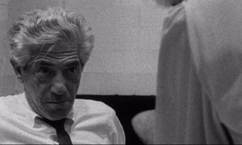 Movie still from “Faces” (1968), directed by John Cassavetes – An older man wearing a white shirt and a tie; Close Up shot, Over the shoulder angle