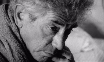Movie still from “Faces” (1968), directed by John Cassavetes – An older man is looking at the camera with his hand on his chin; Close Up shot, High angle