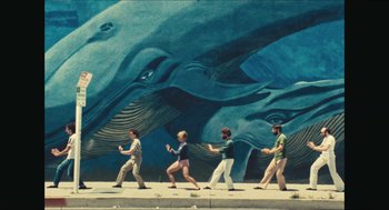 Movie still from “Faces Places” (2017), directed by Agnès Varda – A group of people walking in front of a mural of whales; Extreme Wide shot, High angle