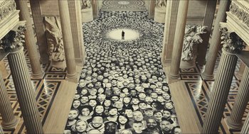 Movie still from “Faces Places” (2017), directed by Agnès Varda – A man standing in front of a floor covered in faces; Extreme Wide shot, High angle