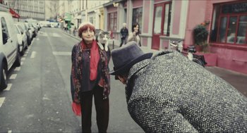 Movie still from “Faces Places” (2017), directed by Agnès Varda – An older woman standing next to a man on the street; Medium shot, Over the shoulder angle