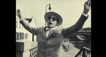 Movie still from “Faces Places” (2017), directed by Agnès Varda – A man in a suit and hat standing on a bridge; Medium shot, Low angle