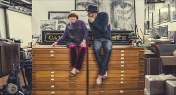 Movie still from “Faces Places” (2017), directed by Agnès Varda – A man and a woman sitting on top of drawers; Wide shot, Overhead angle