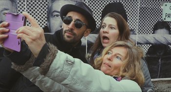 Movie still from “Faces Places” (2017), directed by Agnès Varda – A group of people standing next to each other in front of faces; Close Up shot, Low angle