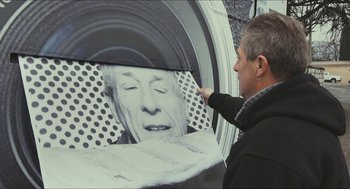 Movie still from “Faces Places” (2017), directed by Agnès Varda – A man is pointing to a picture of a man's face; Medium shot, Low angle
