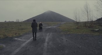 Movie still from “Faces Places” (2017), directed by Agnès Varda – Two people on a dirt road near a large mountain; Extreme Wide shot, Over the shoulder angle
