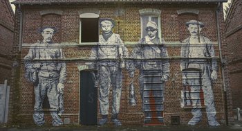 Movie still from “Faces Places” (2017), directed by Agnès Varda – A brick wall with a mural of a man and a woman; Extreme Wide shot, Low angle