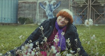 Movie still from “Faces Places” (2017), directed by Agnès Varda – An older woman sitting in a field of flowers; Medium shot, Over the shoulder angle