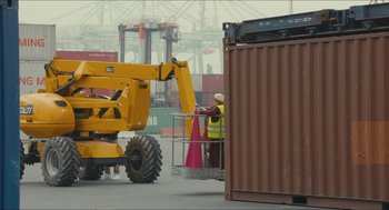 Movie still from “Faces Places” (2017), directed by Agnès Varda – A man standing next to a large yellow crane; Extreme Wide shot, Low angle