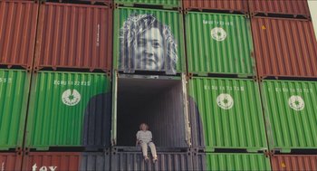 Movie still from “Faces Places” (2017), directed by Agnès Varda – A person sitting in a window of a shipping container; Wide shot, Low angle