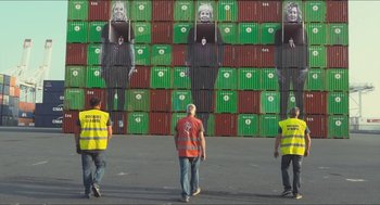 Movie still from “Faces Places” (2017), directed by Agnès Varda – Three men are standing in front of a wall of boxes; Extreme Wide shot, Low angle