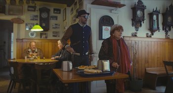Movie still from “Faces Places” (2017), directed by Agnès Varda – A man and a woman standing at a table with food on it; Medium shot, Over the shoulder angle