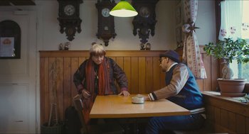 Movie still from “Faces Places” (2017), directed by Agnès Varda – Two people sitting at a wooden table in a restaurant; Medium shot, Over the shoulder angle