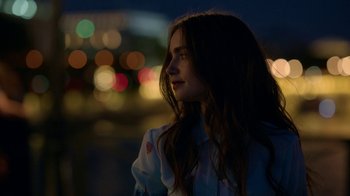 Movie still from “Emily in Paris” (2020), created by Darren Star – A woman standing in front of a city street at night; Close Up shot, Over the shoulder angle