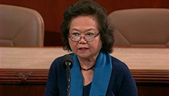 Movie still from “Fahrenheit 9/11” (2004), directed by Michael Moore – An older woman wearing glasses and a blue scarf is speaking; Medium shot, High angle