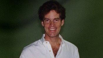 Movie still from “Fahrenheit 9/11” (2004), directed by Michael Moore – A person wearing a white shirt smiling; Close Up shot, High angle