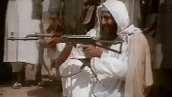 Movie still from “Fahrenheit 9/11” (2004), directed by Michael Moore – A man in white is holding a gun; Medium shot, High angle