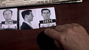 Movie still from “Fahrenheit 9/11” (2004), directed by Michael Moore – A person holding up a picture of a man with a beard; Extreme Close Up shot, High angle