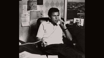 Movie still from “Fahrenheit 9/11” (2004), directed by Michael Moore – A black and white photo of a man talking on a phone; Medium shot, High angle