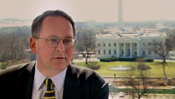 Movie still from “Fahrenheit 9/11” (2004), directed by Michael Moore – A person wearing a suit and tie; Close Up shot, Over the shoulder angle