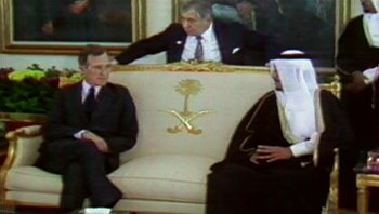 Movie still from “Fahrenheit 9/11” (2004), directed by Michael Moore – A group of men sitting on top of a white couch; Wide shot, Over the shoulder angle