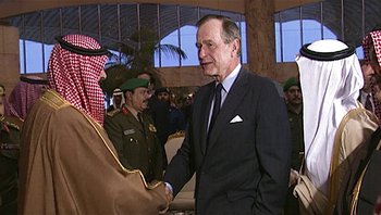 Movie still from “Fahrenheit 9/11” (2004), directed by Michael Moore – A group of men standing next to each other in a room; Medium shot, Over the shoulder angle