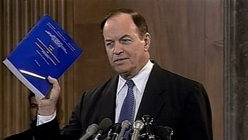 Movie still from “Fahrenheit 9/11” (2004), directed by Michael Moore – A person holding up a book in front of microphones; Close Up shot, Low angle