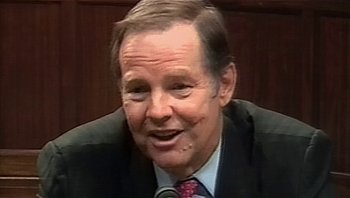 Movie still from “Fahrenheit 9/11” (2004), directed by Michael Moore – An older man wearing a suit and tie; Close Up shot, Over the shoulder angle