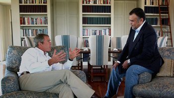 Movie still from “Fahrenheit 9/11” (2004), directed by Michael Moore – Two men are sitting in a room talking to each other; Medium shot, Over the shoulder angle