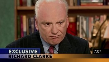Movie still from “Fahrenheit 9/11” (2004), directed by Michael Moore – A man in a black suit and a red tie; Close Up shot, High angle